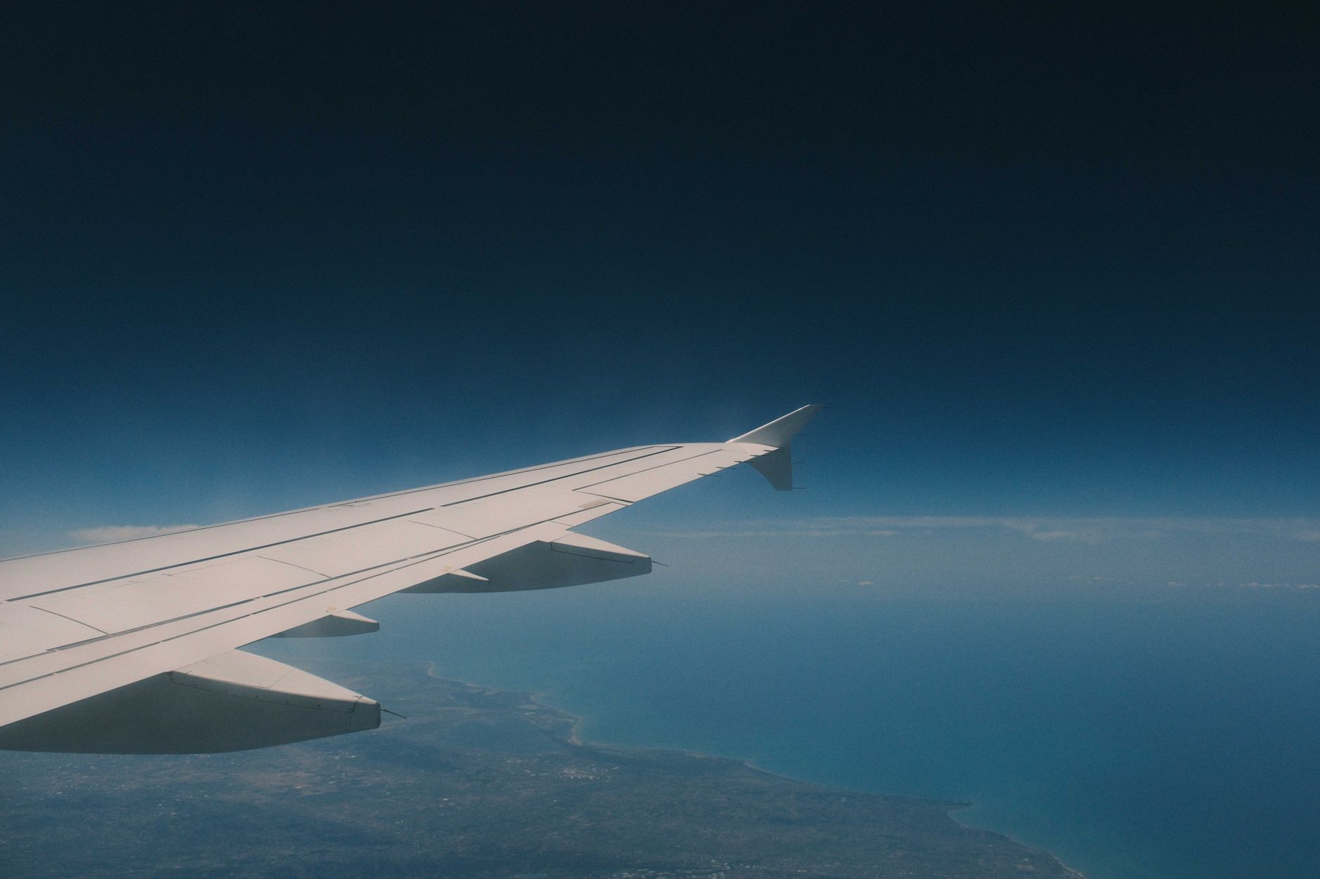 Flugzeugfenster mit Blick auf Wolken über der Tragfläche