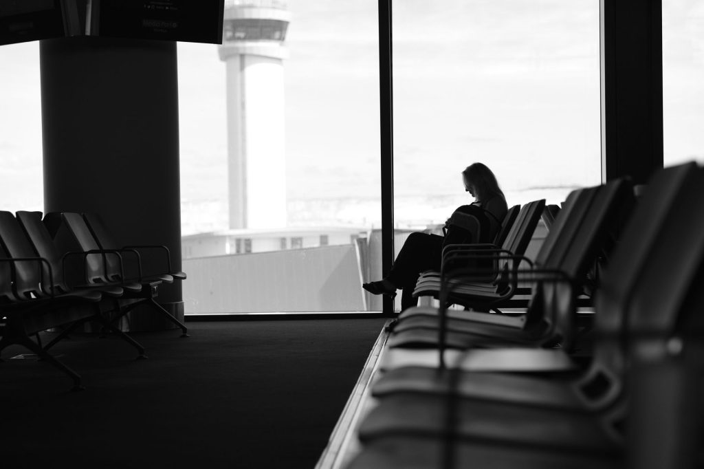 Reisende in einer Flughafen-Lounge mit Blick aufs Vorfeld – Foto: Berk Aktas via Pexels